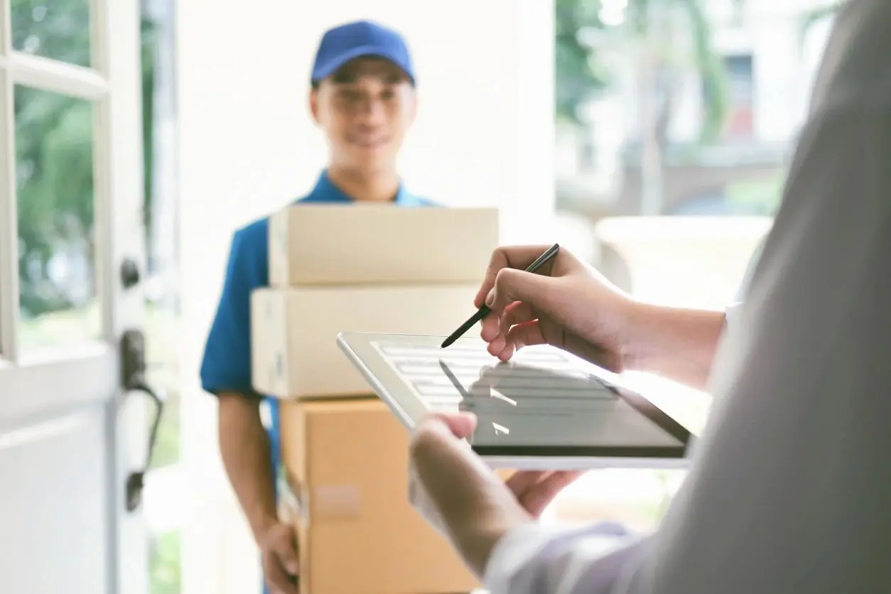 Delivery person handing over packages, customer signing on a clipboard.